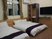 a bedroom with two beds and a flat screen tv at Fengming B&amp;B in Jinning