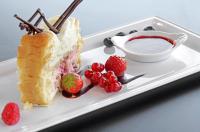 a white plate with a piece of cake and strawberries at Logis Hotel des Bourbons Montluçon Climatisé in Montluçon