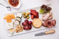 Un plato blanco con diferentes tipos de queso y fruta. en African Rock Hotel & Spa, a "Boutique Lifestyle Resort", en Kempton Park