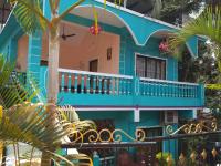 una casa azul con balcón y palmeras en Noel Guest House, en Marmagao