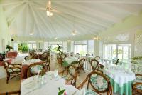 Un comedor con mesas y sillas blancas y ventanas. en Hotel Villa Serena, en Las Galeras