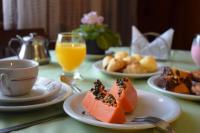 a table with plates of fruit and a cup of orange juice at Pousada Sino dos Ventos in Campos do Jordão