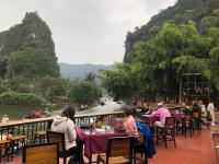 Un grupo de personas sentadas en mesas cerca de un río. en Tam Coc Bungalow, en Ninh Binh