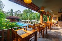 een restaurant met houten tafels en stoelen en een zwembad bij Bauhinia Resort & Spa Phu Quoc in Phu Quoc