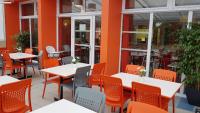 an empty restaurant with white tables and orange chairs at The Originals Access, Hôtel les Iris, Berck-sur-Mer in Berck-sur-Mer