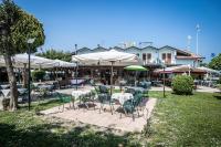 een terras met tafels, stoelen en parasols bij Hotel Johnson in Peschiera del Garda