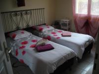 two beds in a bedroom with red flowers on them at La Nouste Maisoun in Barcelonne-du-Gers