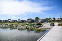 a river with houses in the background and a dock at Slite Strand resort in Slite