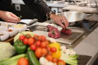 una persona preparando carne en una bandeja en una cocina en H4 Hotel Leipzig, en Leipzig