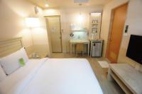 a bedroom with a large bed and a table and a kitchen at Kindness Hotel - Tainan Minsheng in Tainan