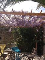a patio with chairs and a pergola with purple flowers at Olive et Pomme in Bretteville