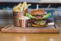 a hamburger and fries on a cutting board with a drink at The Torfin in Edinburgh