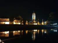 a lit up building with a reflection in the water at night at Baan Baimai Boutique Room in Phra Nakhon Si Ayutthaya
