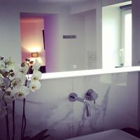 a bathroom with a mirror and a vase of flowers at La Pause Romantique in Dole