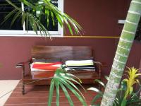 a wooden bench with pillows in a room with a palm tree at Baan Baimai Boutique Room in Phra Nakhon Si Ayutthaya