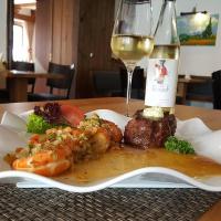 un plato de comida con una copa de vino blanco en Hotel Weinhaus Weis, en Leiwen