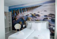 a bedroom with a large painting of a pier at City2Beach Hotel in Vlissingen