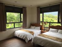 two beds in a room with large windows at 闕麒景觀民宿Chill Villa B&amp;B in Puli