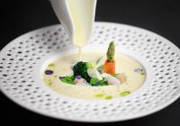 a white bowl of soup with sauce being poured on it at Hotel Golden Key, 4 Stars Superior in Nitra