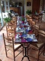a long wooden table with chairs and plates on it at La Grande Mare in Saint-Benoît-des-Ondes