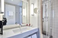 a white bathroom with a sink and a shower at Hotel &amp; Spa Vacances Bleues Le Splendid in Dax