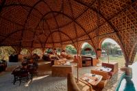 雅拉Wild Coast Tented Lodge - Relais and Chateaux - All Inclusive的一家有着大型茅草屋顶、摆放着桌椅的餐厅