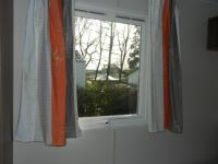 a window with an orange and white curtain at Mareva37 in Trogues