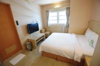 a hotel room with a bed and a television at Kindness Hotel - Tainan Minsheng in Tainan
