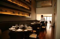 萨尔塔艾尔代萨尔塔酒店的一个男人站在一家摆放着桌椅的餐厅里。