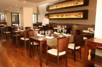 萨尔塔艾尔代萨尔塔酒店的一名男子站在摆着桌椅的餐厅里