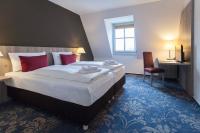 Una habitación de hotel con una cama grande con almohadas rojas. en martas Hotel Lutherstadt Wittenberg, en Lutherstadt Wittenberg