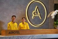 dos personas de pie detrás de un mostrador en un hotel en Aerotel Kuala Lumpur (Airport Hotel) - Gateway@klia2, en Sepang