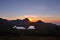 a sunset over a mountain with a road and a lake at Casa Rural Priena in Covadonga