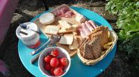 a blue plate topped with cheese and a basket of tomatoes at Résidence de Vaux in Nans-sous-Sainte-Anne