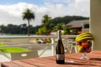 a bottle of wine sitting on a table with a bowl of fruit at Crow&#39;s Nest Apartments in Whitianga