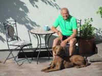 a man sitting on a chair next to a dog at Ferienwohnung Familie Wieser in Altenmarkt im Pongau