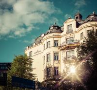 a tall white building with the sun shining on it at Hotel Kung Carl, WorldHotels Crafted in Stockholm
