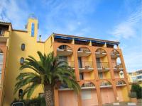 a yellow building with a palm tree in front of it at Hotel Alhambra in Cap d&#39;Agde