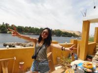 a woman standing on a boat with her arms outstretched at Hamo Guest House in Aswan