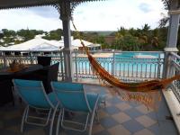 a hammock on a porch with a view of the pool at Appartement à la Résidence LA PLANTATION RESORT and SPA in Saint-François