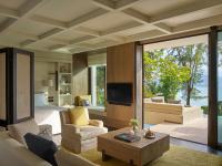 a room with a bed and a living room with a tv at Rosewood Phuket in Patong Beach