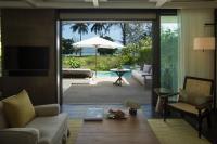 a living room with a couch and a table with an umbrella at Rosewood Phuket in Patong Beach
