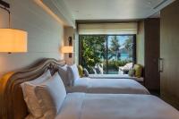 a hotel room with two beds and a large window at Rosewood Phuket in Patong Beach