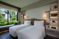 two beds in a bedroom with a large window at Rosewood Phuket in Patong Beach