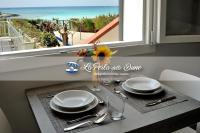 a table with plates and glasses and a window with the ocean at La Perla delle Dune (Sul Mare) in Porto Cesareo