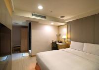 a bedroom with a large white bed and a desk at Shihzuwan Hotel – Kaohsiung Station in Kaohsiung