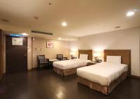 a hotel room with two beds and a table and chairs at Shihzuwan Hotel – Kaohsiung Station in Kaohsiung