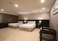a hotel room with two beds and a desk at Shihzuwan Hotel – Kaohsiung Station in Kaohsiung