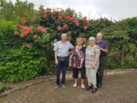 a group of people standing in front of a rose bush at Hôtel-Logis La Coraline in Gannat