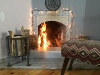 a fireplace with a fire in it with christmas lights at Hotel Lemi in Mestia